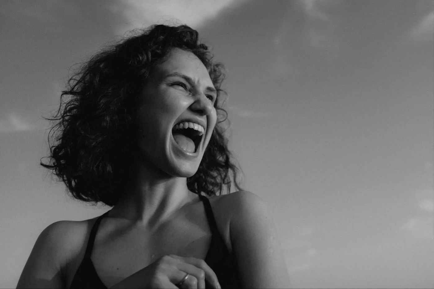 A woman laughing out loud against an open sky.