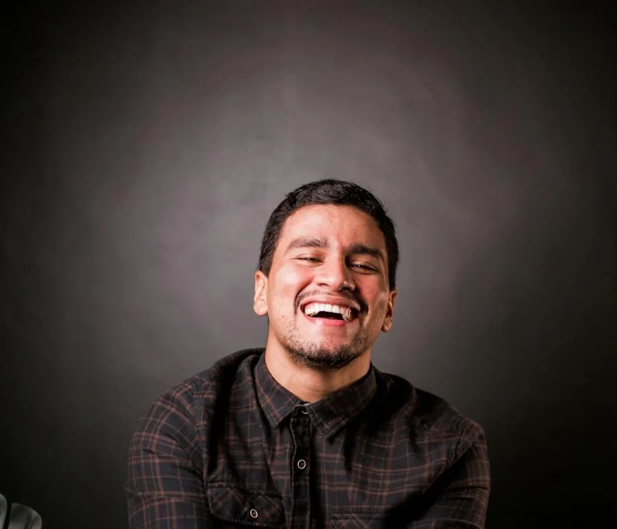 A man laughing in a dark studio.