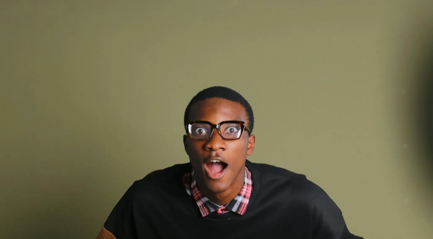 A man in glasses, wide-eyed with surprise.